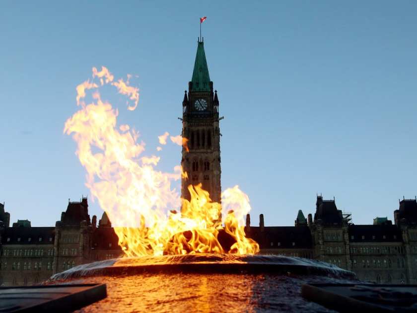 The Centre Block of the Parliament Buildings is shown through the Centennial Flame on Parliament Hill in Ottawa .